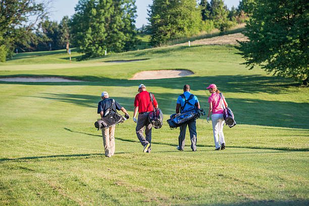 Four golfers walking on the golf course. Rear View.